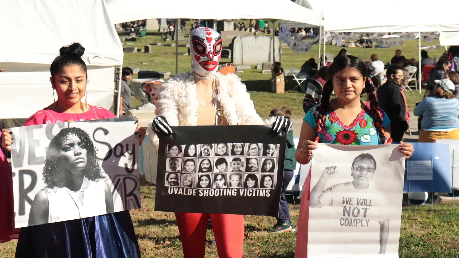 Three people holding images of people who have been killed by gunmen