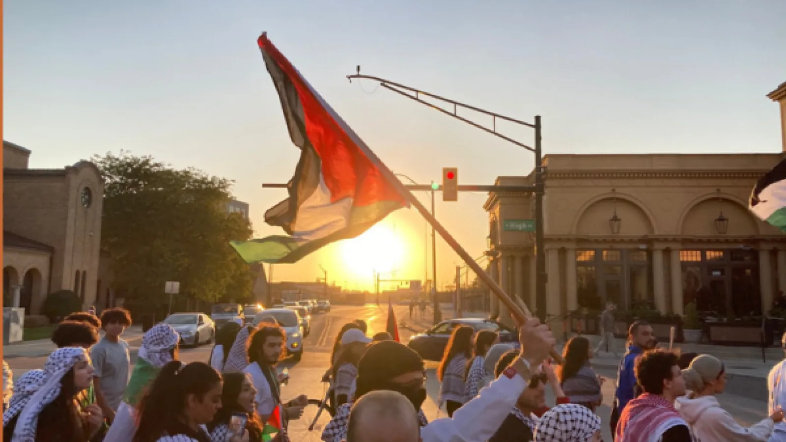 People crowded into a street are waving the Palestinian flag