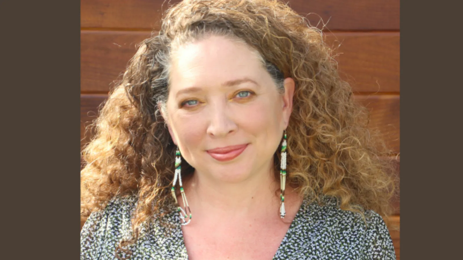 Woman with long light brown hair and blue eyes smiling
