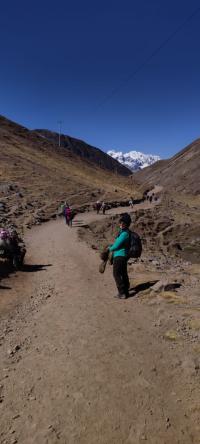 A woman standing before the Andes mountains on a dirt road