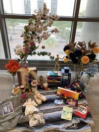A day of the dead alter or ofrenda with a variety of items splayed across a mexican striped woven blanket