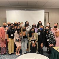 Group shot of 18 people wearing face masks in front of a projector screen