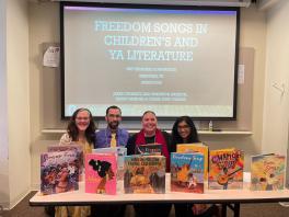 Four people standing behind a row of children's books on diversity