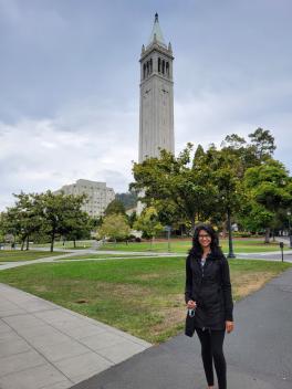 Woman standing on a city street with a tall tower in the distance