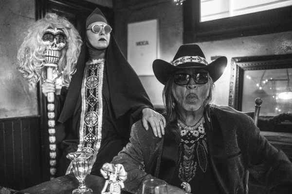 A woman holding a skull on a staff and a man wearing a cowboy hat