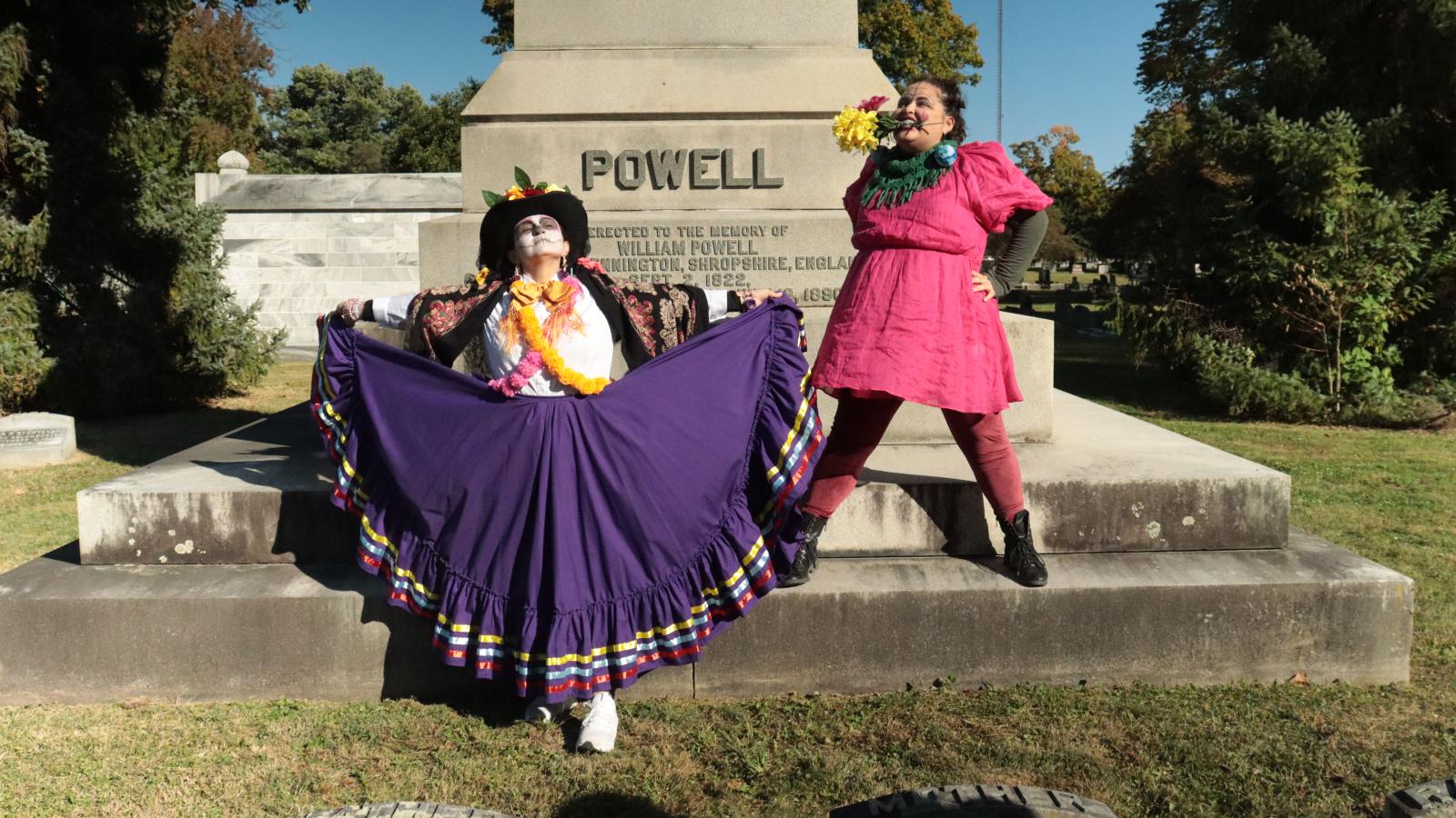 Two dancers in front of a large cemetery monument
