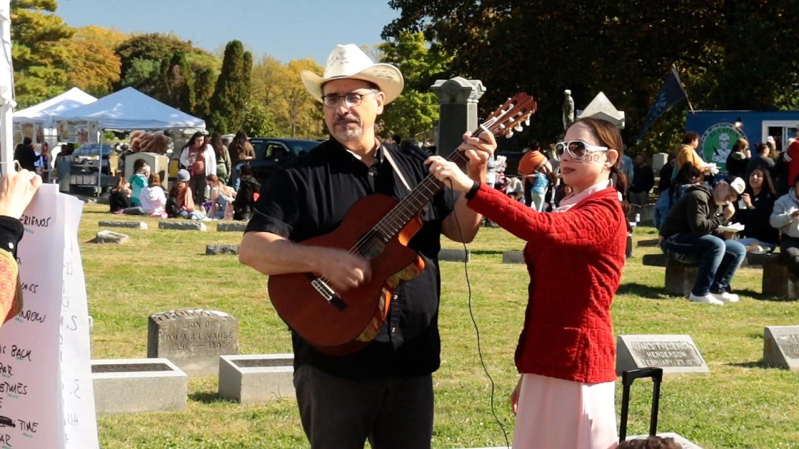 A man playing guitar next to a woman in a red jacket