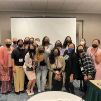 Group of 18 people wearing face masks in front of a projector screen